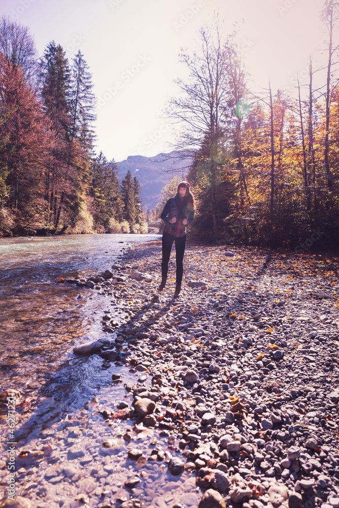 Woman wearing red woolly hat and denim jacket walking at riverside in autumn Woman wearing red woolly hat and denim jacket walking at riverside in autumn