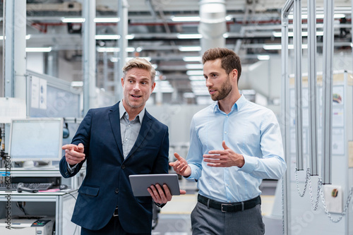 Two businessmen with tablet talking in a modern factory photo