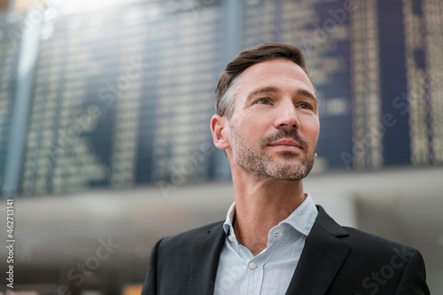 Portrait of businessman at arrival departure board at the airport photo