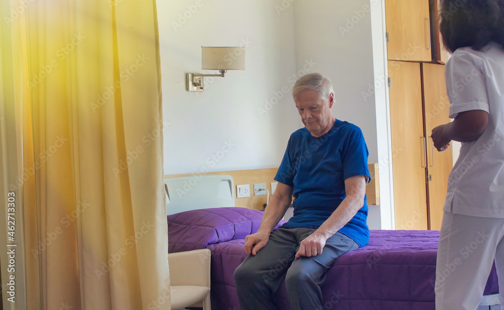 African female doctor helping elderly male patient in hospital bed. Rehabilitation and retirement concept African female doctor helping elderly male patient in hospital bed. Rehabilitation and retirement concept