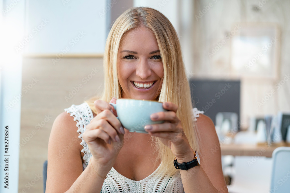 Portrait of smiling blond woman drinking coffee in a cafe Portrait of smiling blond woman drinking coffee in a cafe