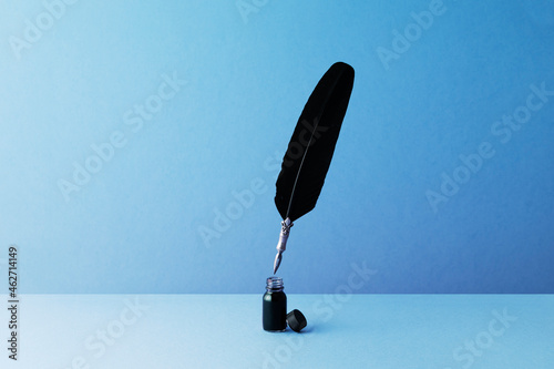 Quill pen and inkwell over blue background photo