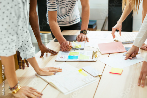 Close-up of colleagues working together at desk in office discussing papers