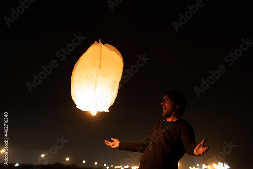 Excited man with floating sky lantern at night photo