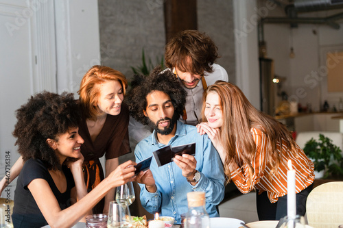 Friends sitting at dining table, looking at photographs