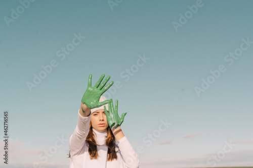 Young woman showing green painted palms photo