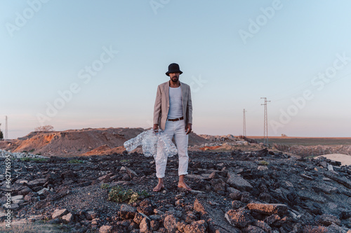 Young man holding empty plastic bottles in barren land photo
