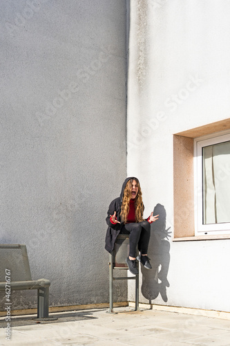 Screaming teenage girl sitting in a corner photo