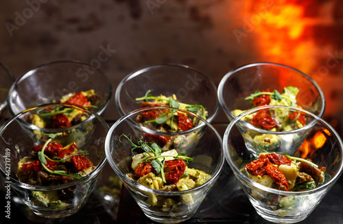A light snack of potatoes, cucumbers, chili peppers, chicken meat and herbs in transparent serving cups.