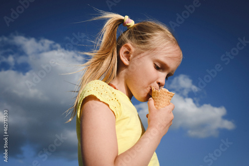 Portrait of blond girl eating ice cream against sky photo