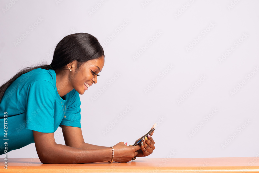 beautiful young black woman resting on a desk and using her phone beautiful young black woman resting on a desk and using her phone