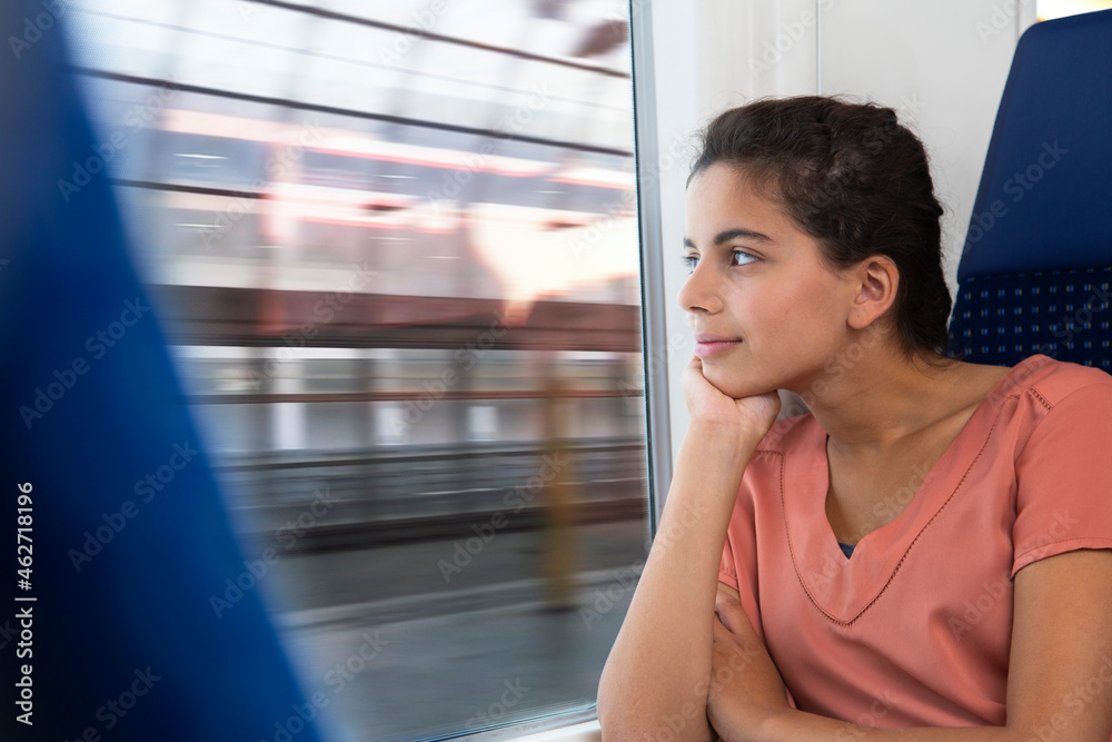 Teenage girl traveling alone by train, looking out of window Teenage girl traveling alone by train, looking out of window