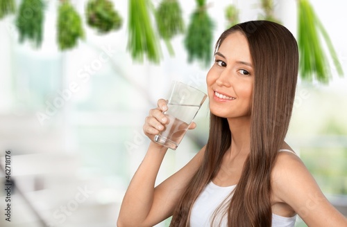 Smiling pretty woman holds a glass of water on kitchen