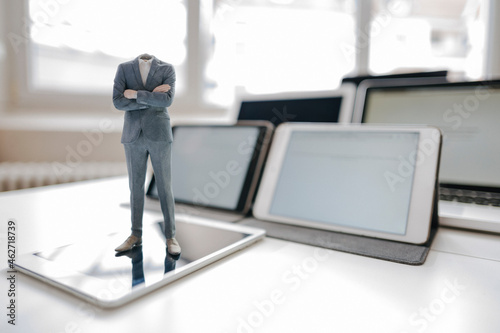 Headless businessman figurine standing on digital tablet on a desk photo