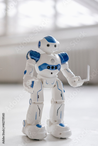 Miniature robot figurine holding laptop