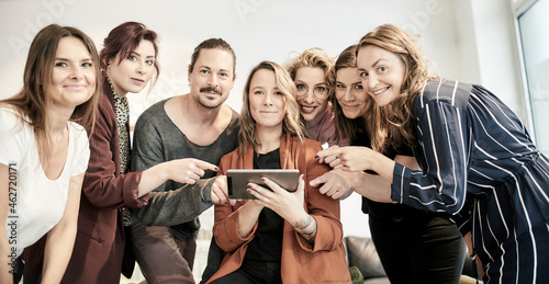 Portrait of colleagues pointing at mini tablet