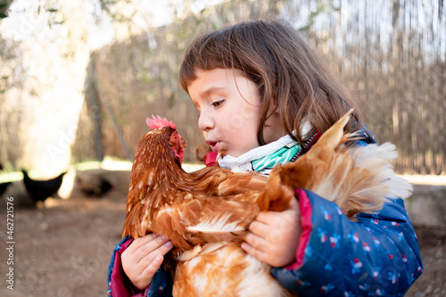 Toddler girl talking to chicken on her arms