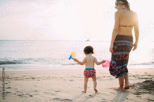 Thailand, Koh Lanta, back view of baby girl and mother on the beach by sunset photo