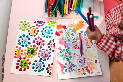 Little girl drawing  ugly viruses with color markers at home photo