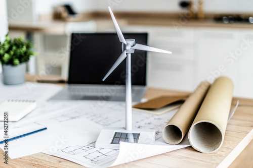 Wind turbine model, construction plan and laptop on table in office photo