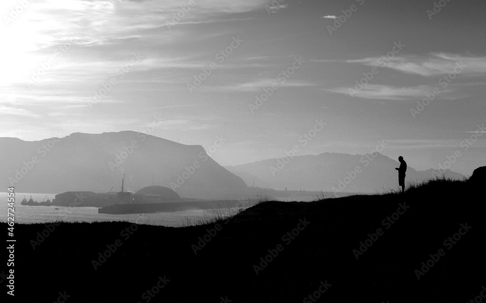 silhouette of a person standing on a cliff tops