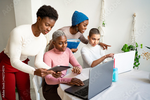 Female colleagues discussing while working in living room