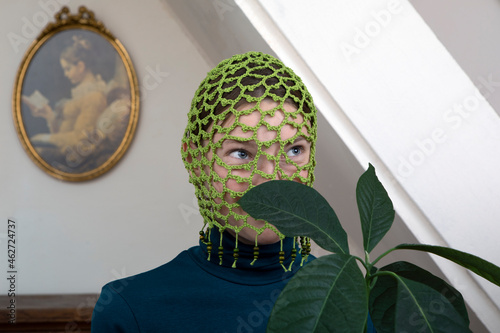 Portrait of teenage girl with avocado plant wearing crocheted green headdress