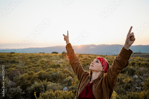 Woman with raised arms in the countryside looking up photo