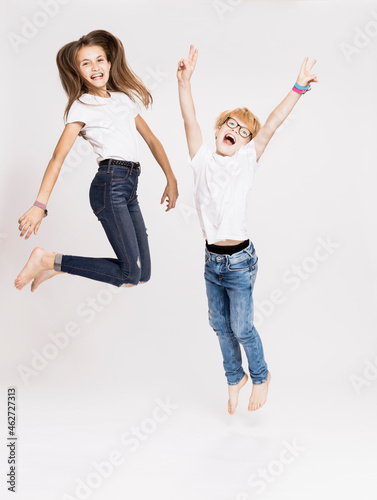 Cheerful siblings jumping against white background