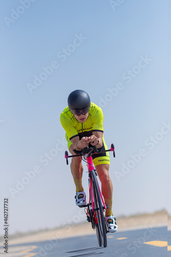 Determined male cyclist riding bicycle on road at desert, Dubai, United Arab Emirates photo