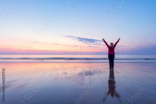 Mature woman with arms raised standing at Seacliff Beach, North Berwick, Scotland during sunset photo