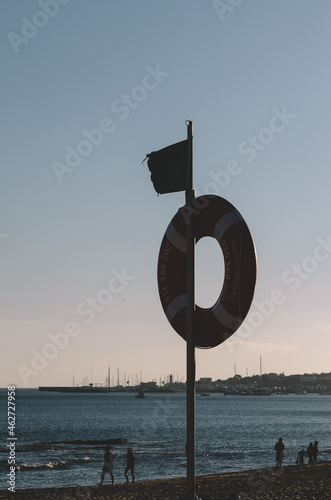 Vertical shot of a lifebuoy attached to a flagpole at the beach in Cascais, Portugal during sunset photo