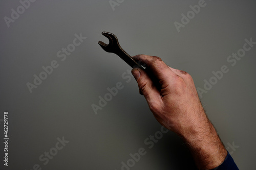 Top view of hand holding screw wrench in front of grey background photo