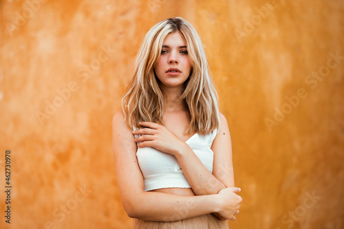 Beautiful blond woman standing against yellow wall