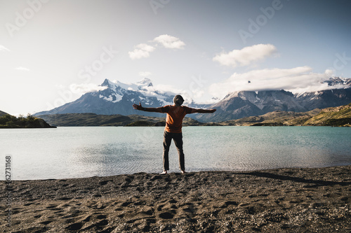 Man with arms outstretched standing at Lake Pehoe in Torres Del Paine National Park Patagonia, South America