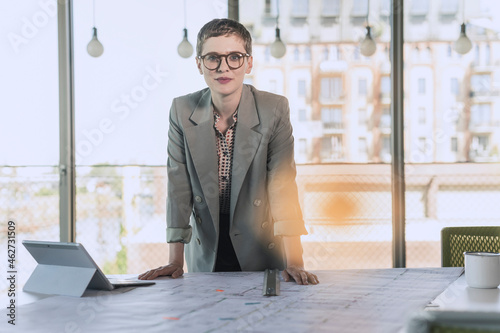 Portrait of confident businesswoman leaning on desk in office photo