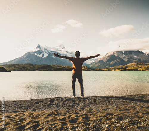 Man standing with arms outstretched at lake Pehoe in Torres Del Paine National Park Patagonia, South America photo