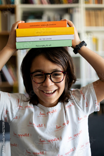 Portrait of laughing boy with stack of books on his head photo