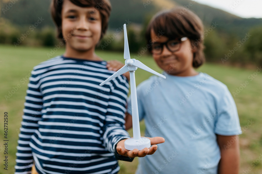 Smiling boys holding windmill toy while standing at backyard Smiling boys holding windmill toy while standing at backyard