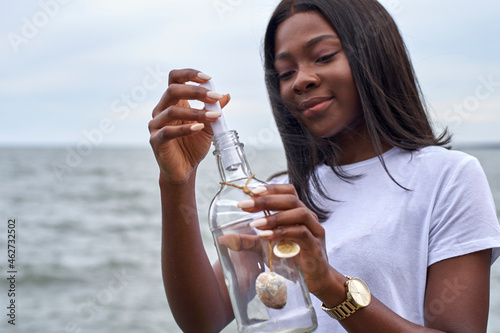 Portrait of young woman in front of the sea sending message in a bottle photo