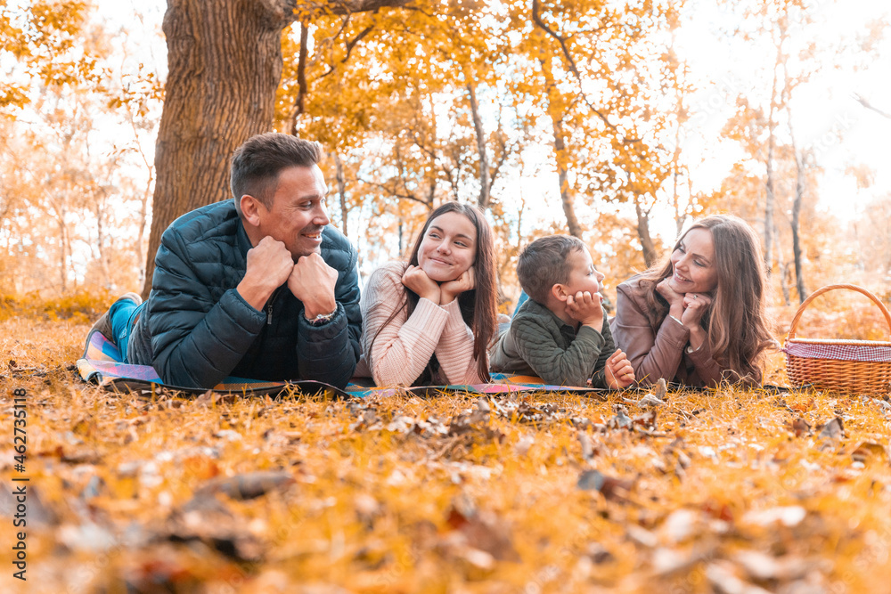 Family with hand on chin lying down in park during autumn Family with hand on chin lying down in park during autumn