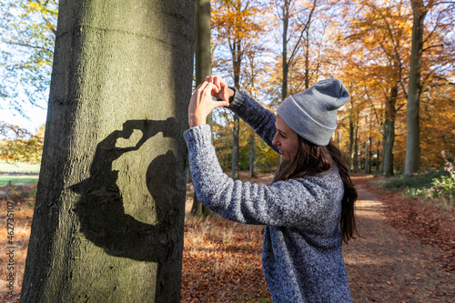 Female hiker making heart shape while standing in Cannock Chase woodland during autumn photo