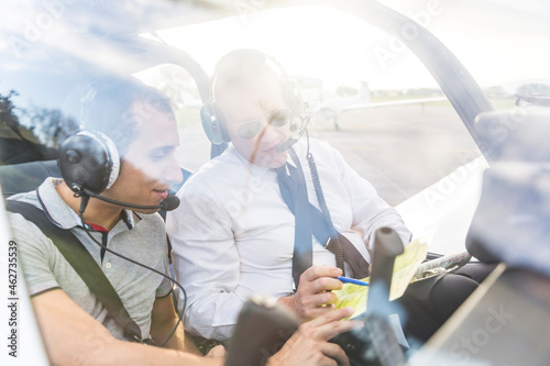 Plot and copilot sitting in sports plane, going through check list photo