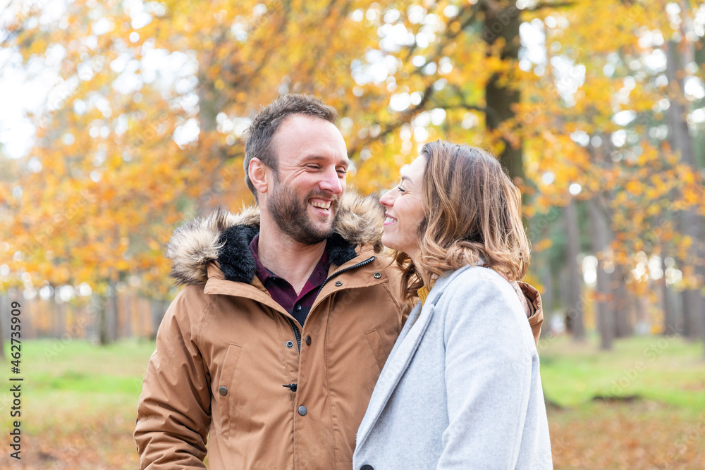 Smiling couple looking at each other while standing in forest Smiling couple looking at each other while standing in forest