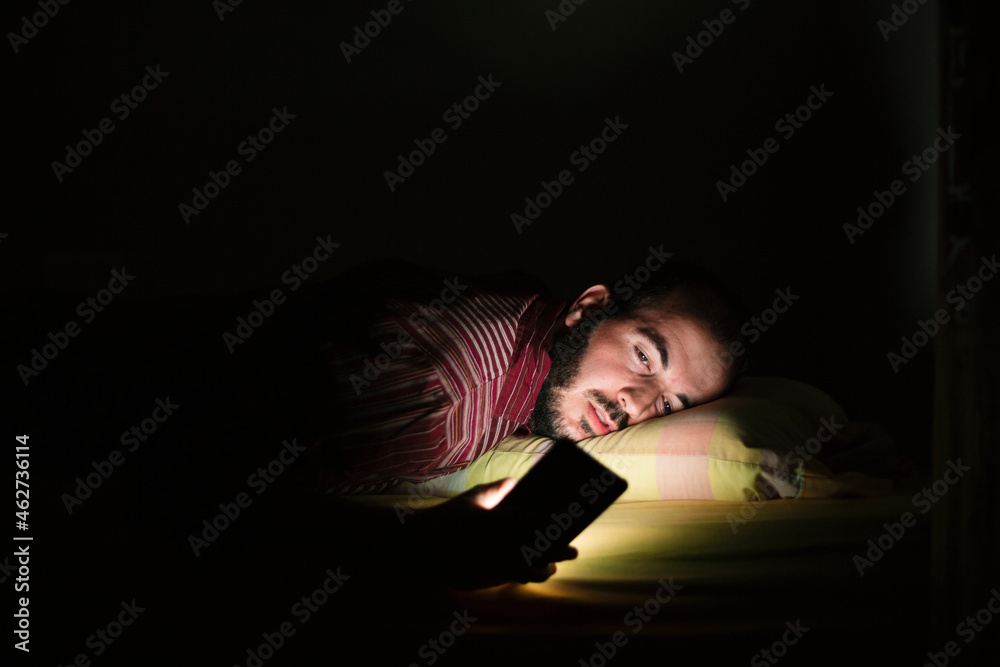 Man lying in bed using smartphone at night Man lying in bed using smartphone at night