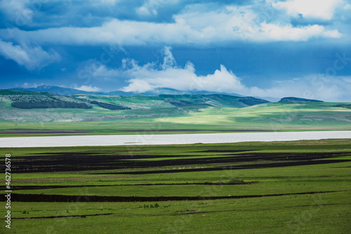 Georgia, Samtskhe-Javakheti, Poka, Green grassy plateau with lake and hills in background