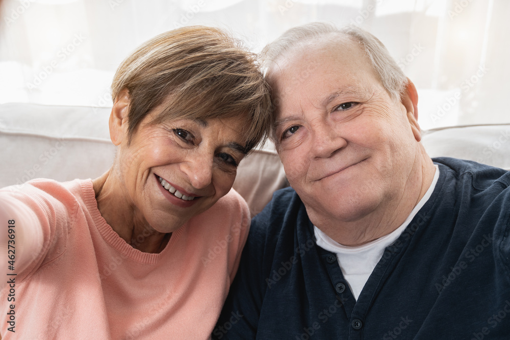 Happy senior couple taking a selfie with mobile phone at home - Real people, elderly lifestyle concept Happy senior couple taking a selfie with mobile phone at home - Real people, elderly lifestyle concept