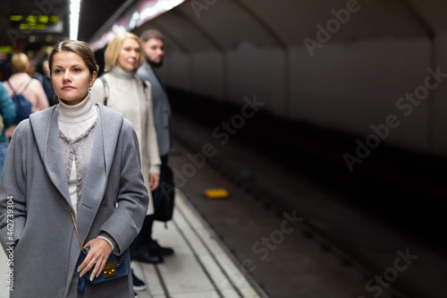 Attractive brunette waiting for train on platform of underground station ..