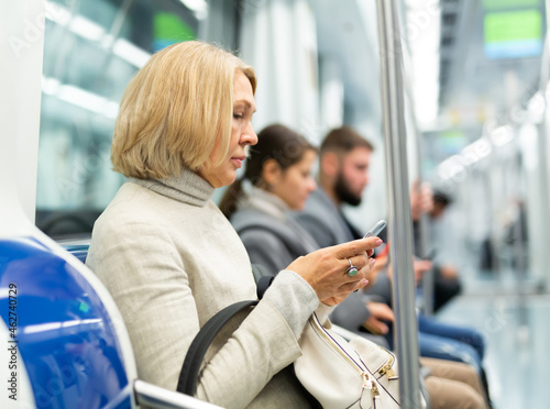 Portrait of female passenger using mobile phone in subway. High quality photo