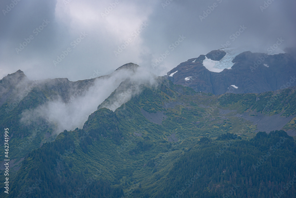 View of mountain peak surrounded by clouds in Alaska, USA. View of mountain peak surrounded by clouds in Alaska, USA.